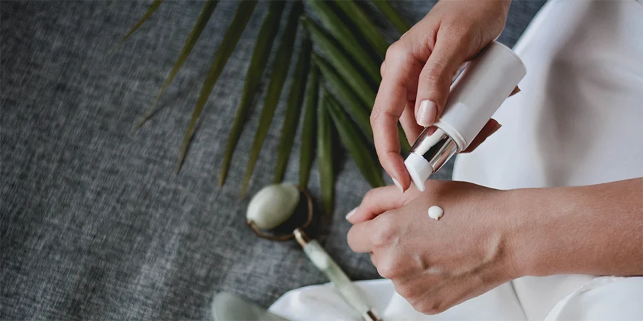 person holding skincare cream bottle - 1